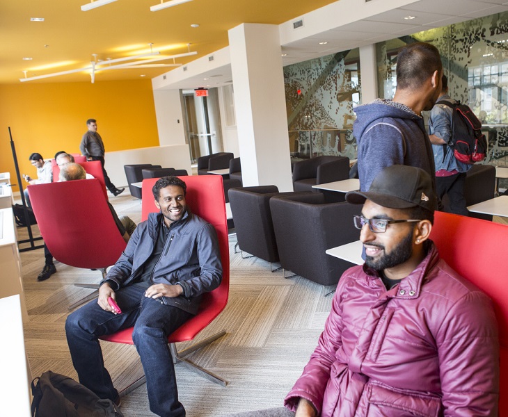 Smiling students sitting on chairs in the Friends of the library room